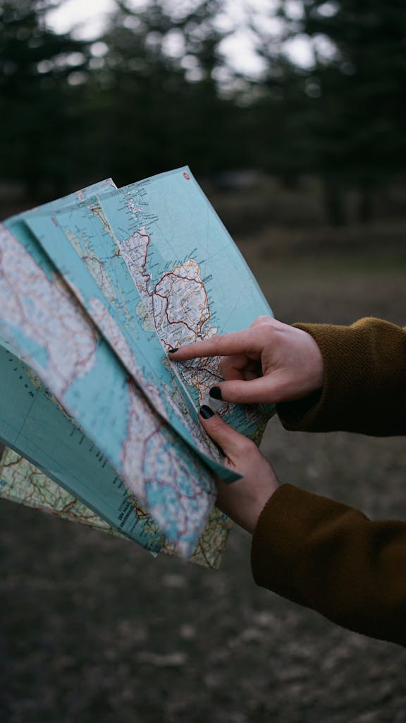 Close-up of hands pointing at a map outdoors, suggesting exploration or travel planning.